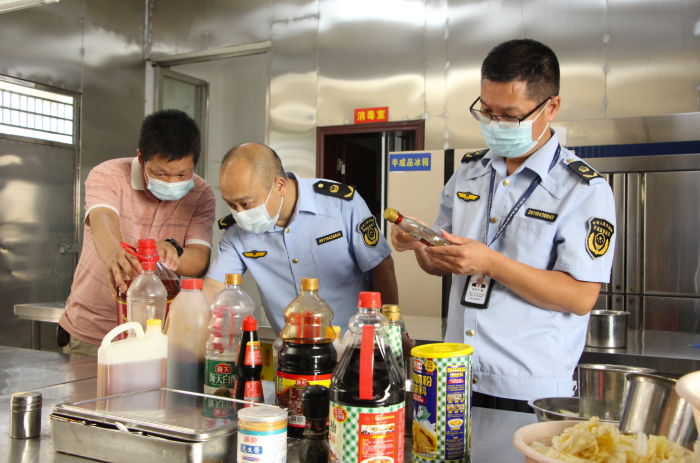 图为该局执法人员在一家餐饮服务单位检查调味料的保质期。