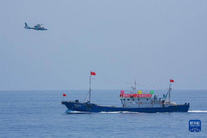 中国海军第40批护航编队中的舰载直升机在被护船只周边海域巡逻警戒（2022年6月4日摄）。新华社发（唐文 摄）