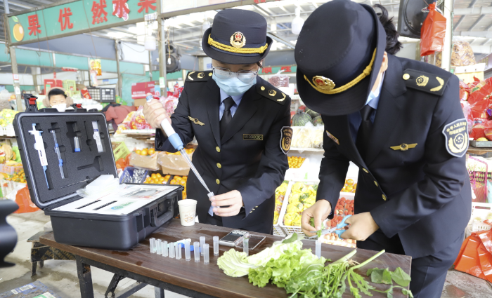 图为该局执法人员对食用农产品样品开展快速检测。