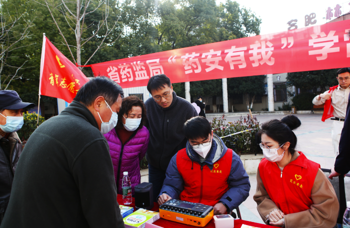 图为安徽省药监局青年志愿者为小区居民现场校准家用电子血压测量仪。