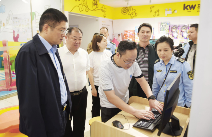 图为湖南省药监局副局长覃永忠（左一）查看化妆品经营户产品质量台账。