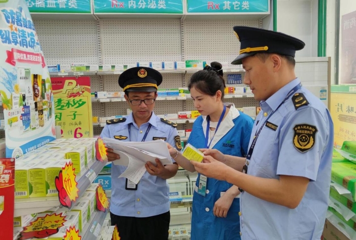 图为6月5日执法人员在一家药店检查防暑药品质量情况。