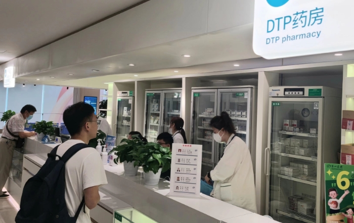 图二为上海第一医药商店的DTP药房和双通道医保区域，执业药师正为顾客提供合理用药指导。