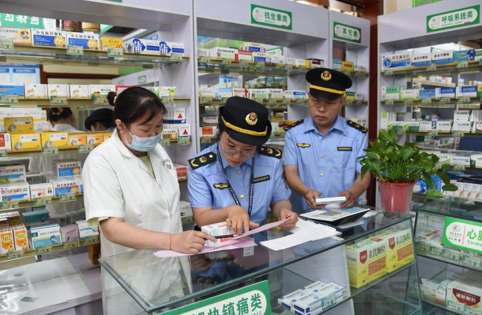 图为执法人员在一家药品零售企业检查药品购进渠道情况。