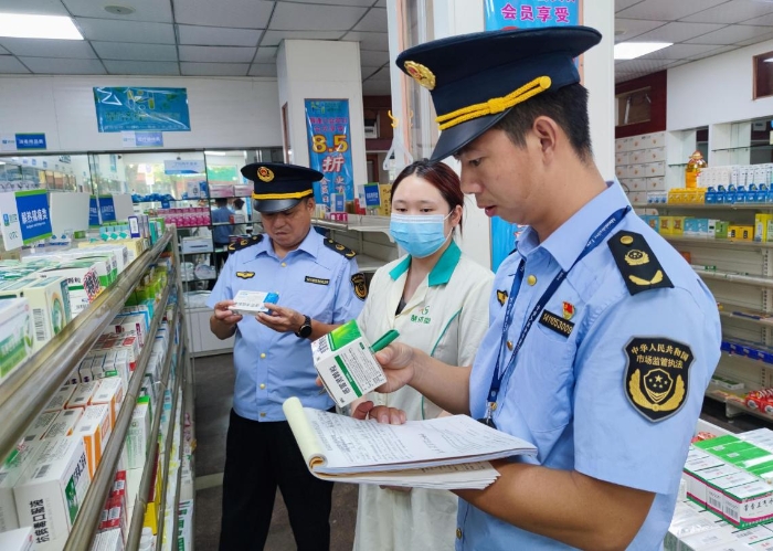 图为执法人员在一家药店检查抗病毒药品质量。