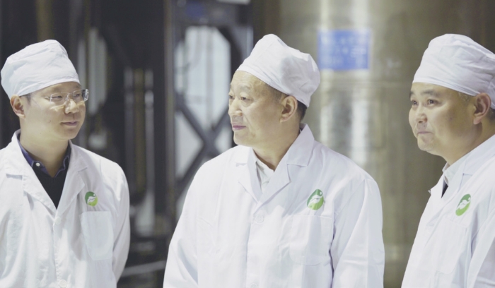 图为新绿色药业董事局主席周厚成（中）、董事长周翔（左）、厂长陈春潮（右）在生产车间。