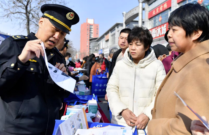 图为主办方执法人员在活动现场向群众科普药械知识。