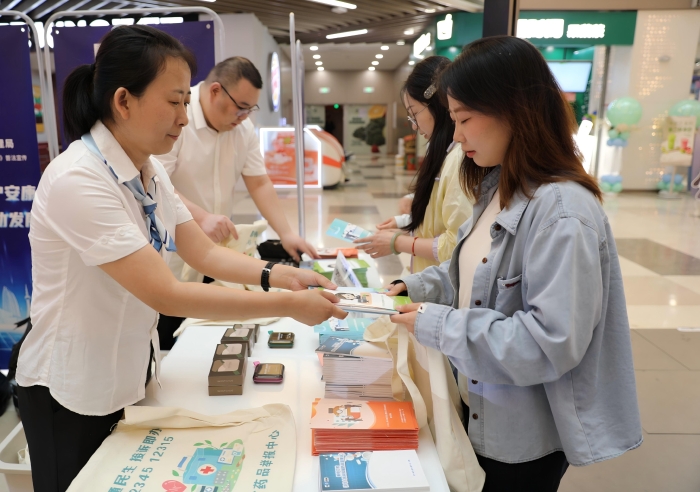 图为工作人员向市民发放《药品管理法实施条例》解读以及用药安全科普知识宣传手册。（叶阳欢摄）