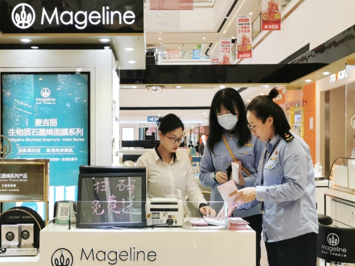 图为工作人员向化妆品经营者宣贯《化妆品监督管理条例》。