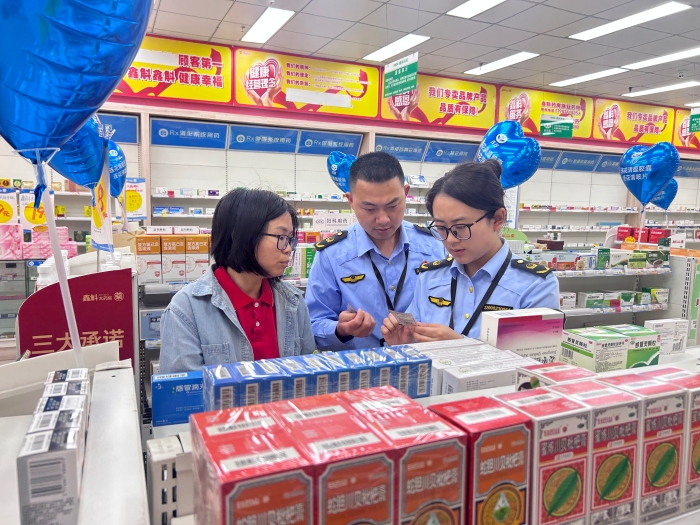 图为5月13日，执法人员在一家零售药店通过核查药品标签检查药品质量